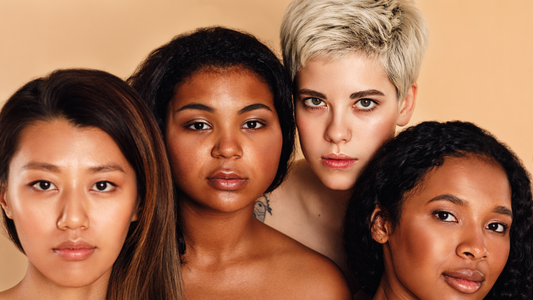 four diverse women looking at the camera with a beige background