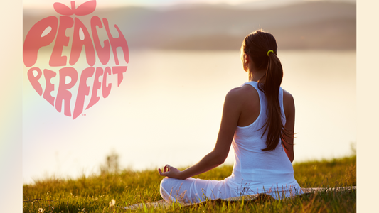 "Young woman sitting in a cross-legged pose with her back to the camera, watching a sunset, symbolizing relaxation and mindfulness in fitness